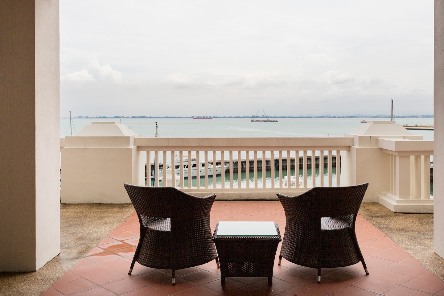 Two wicker chairs on the apartment’s private terrace facing the marina and sea
